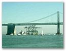 Shipping cranes sail under Bay Bridge